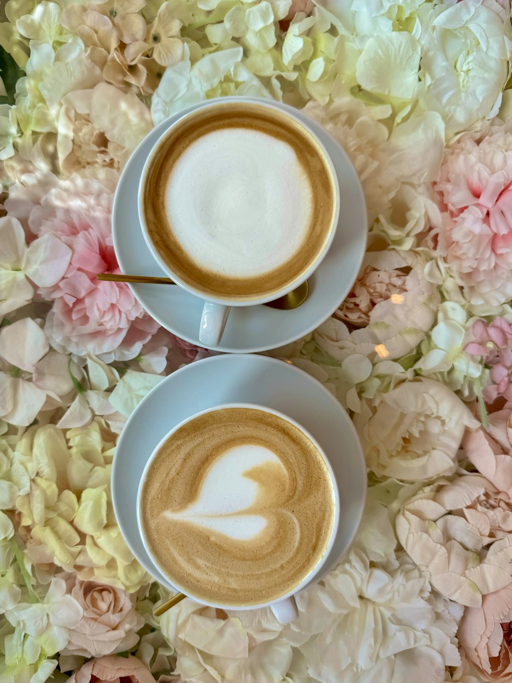 two cups of coffee on a table with flowers