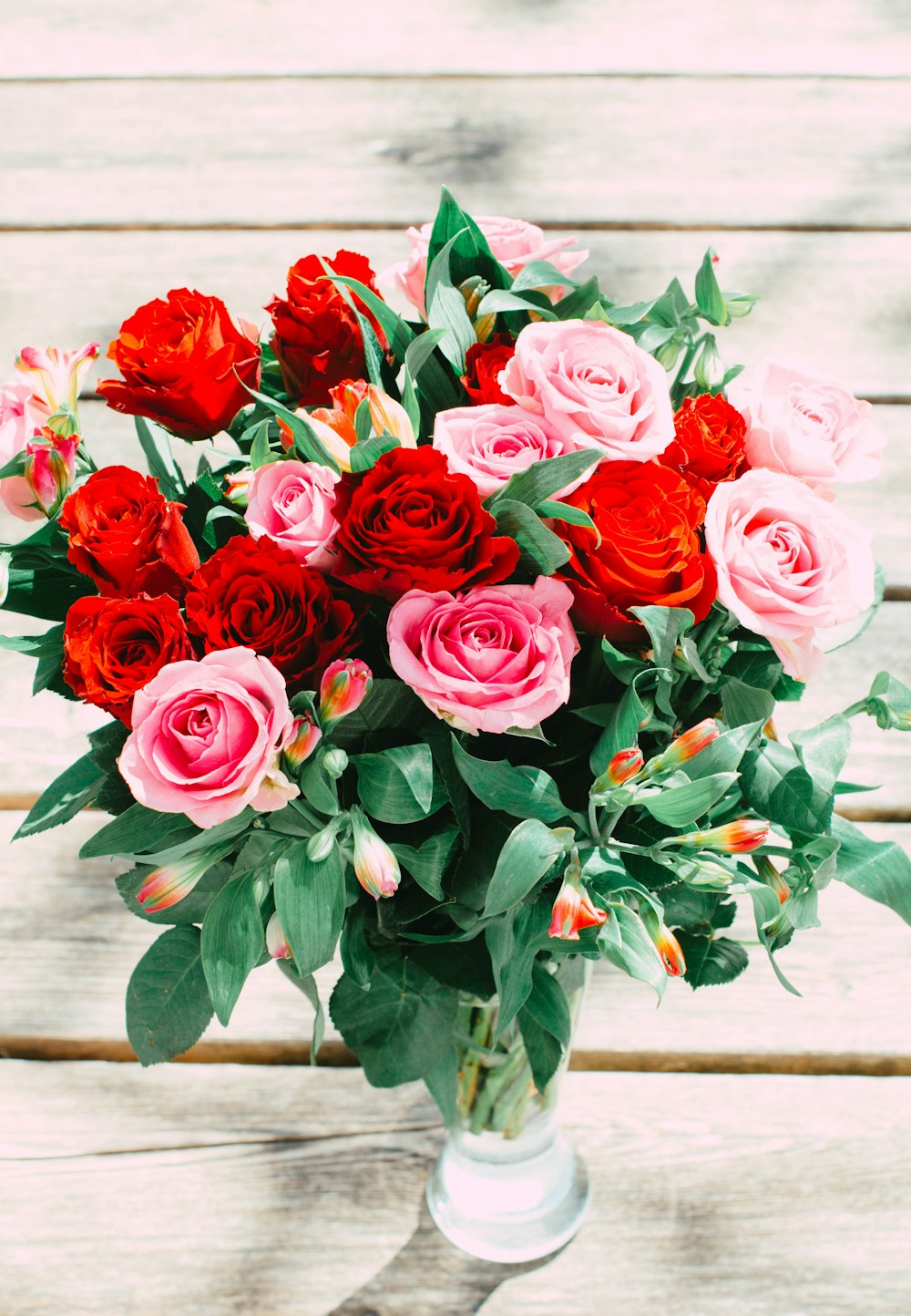 a bouquet of red and pink roses in a vase