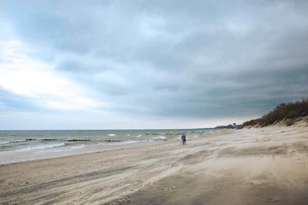eine Person, die an einem Strand neben dem Meer steht