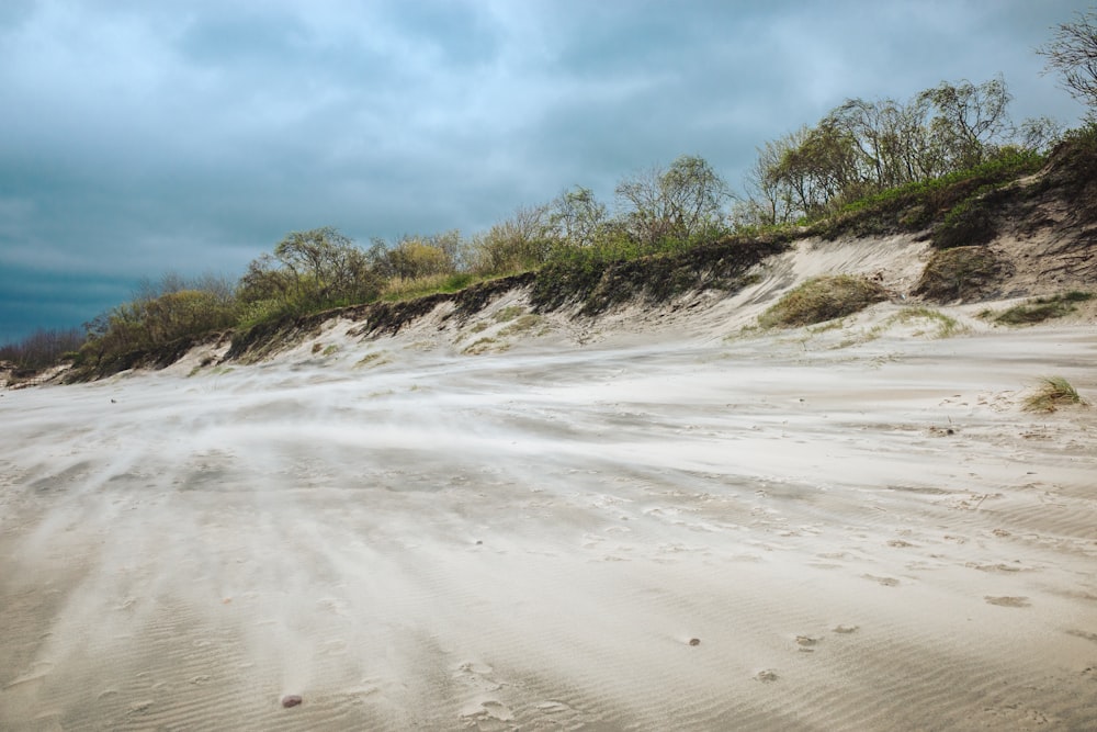 a sandy beach covered in white sand under a cloudy sky