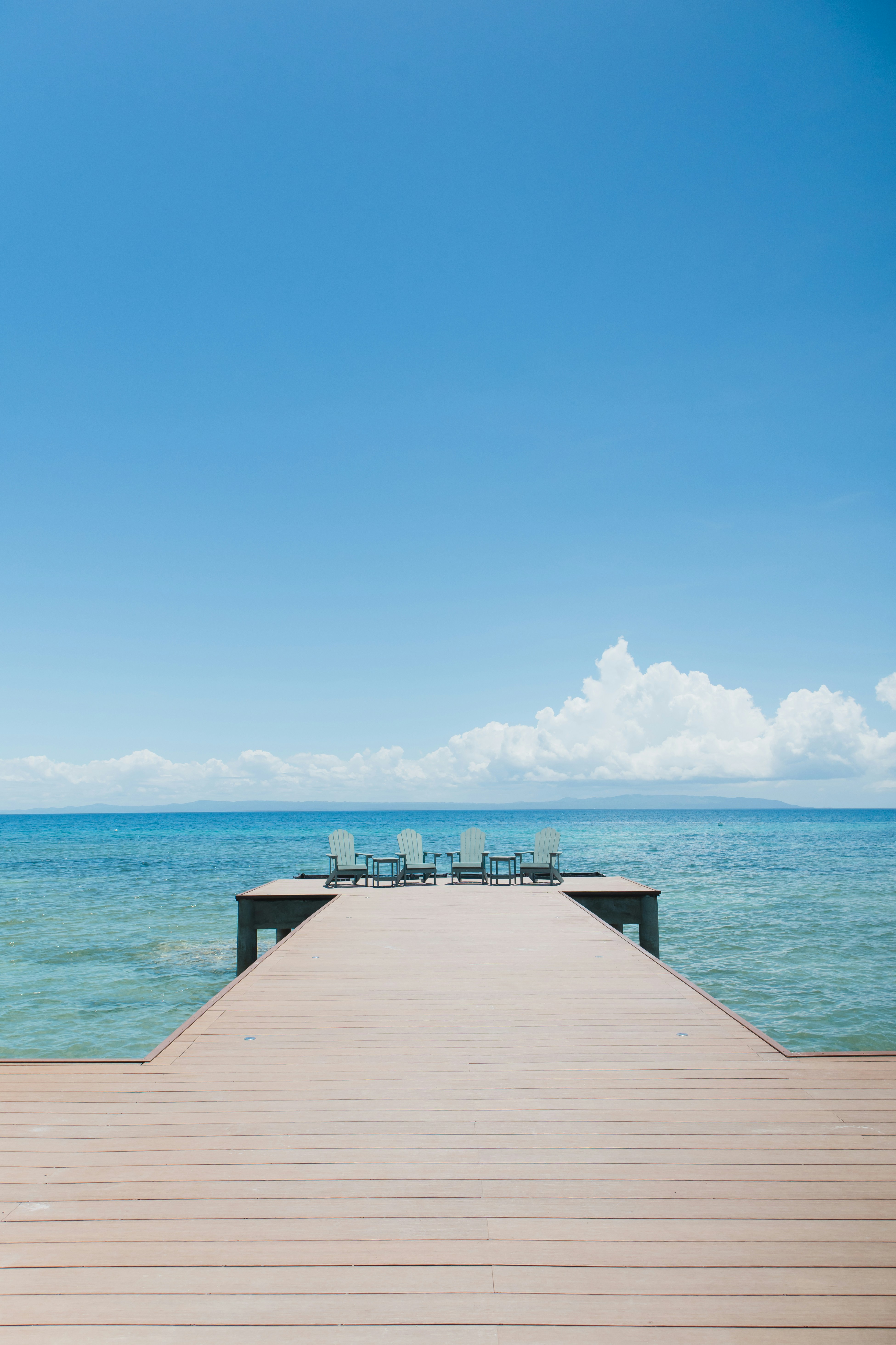 a wooden pier with chairs on top of it