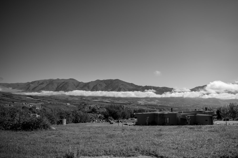 a black and white photo of a farm with mountains in the background