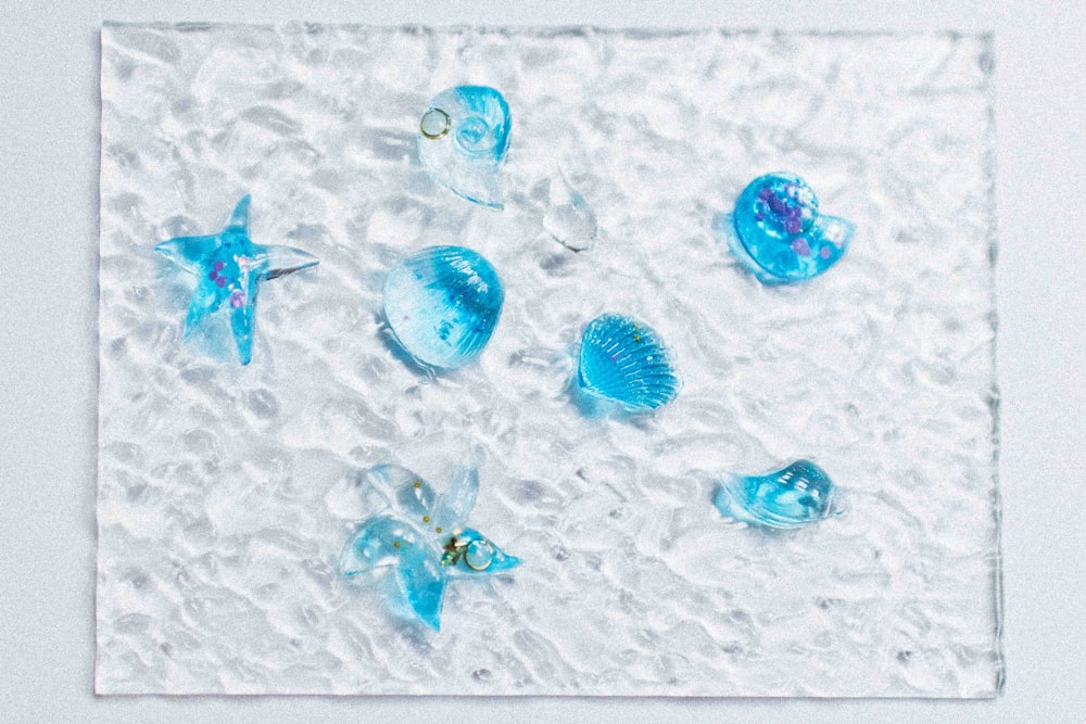 un grupo de adornos de vidrio azul sobre una superficie blanca