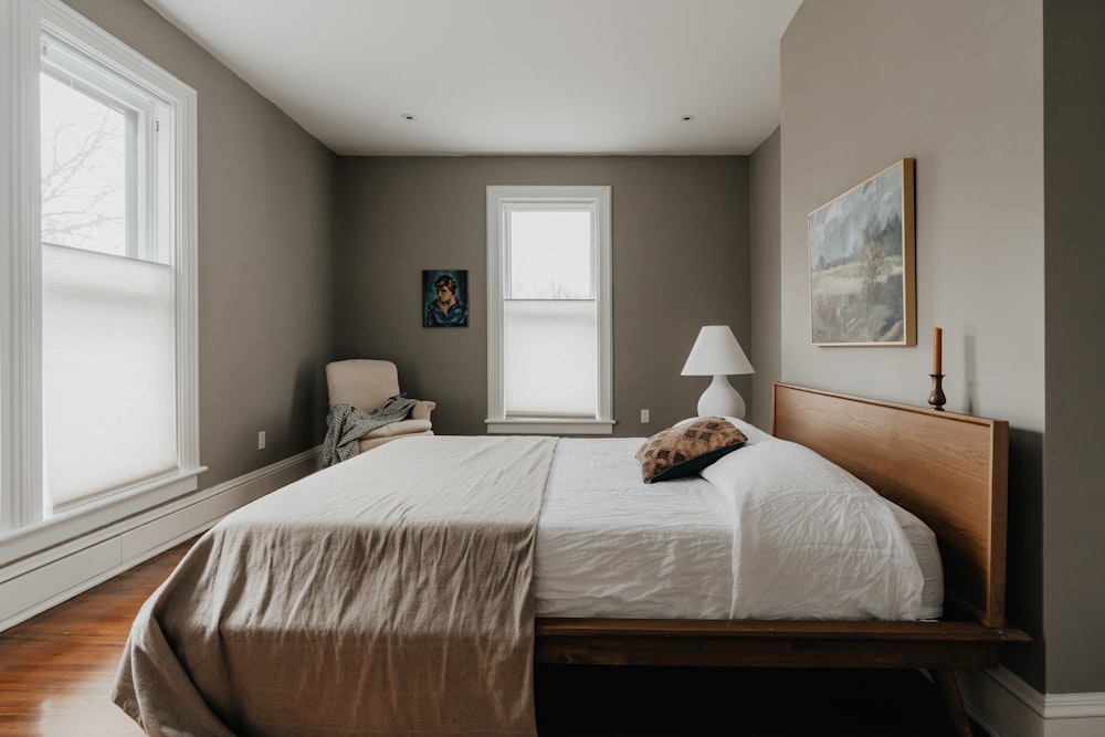 a bed sitting in a bedroom next to two windows