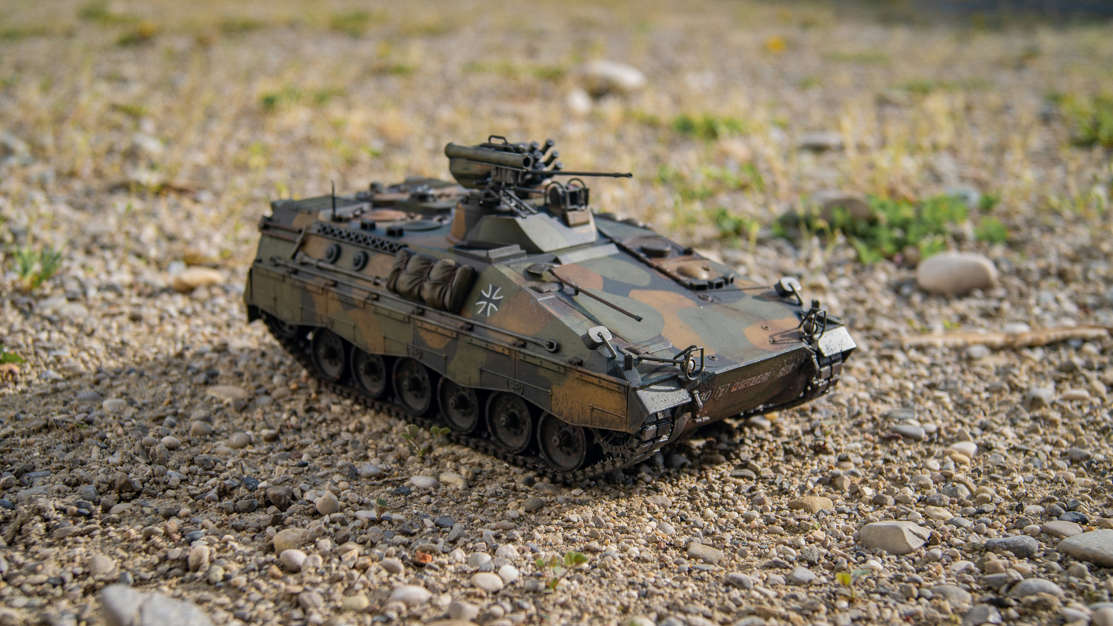 um tanque de brinquedo sentado em cima de um campo de cascalho