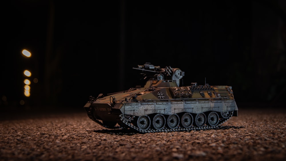 a toy tank sitting on top of a dirt field