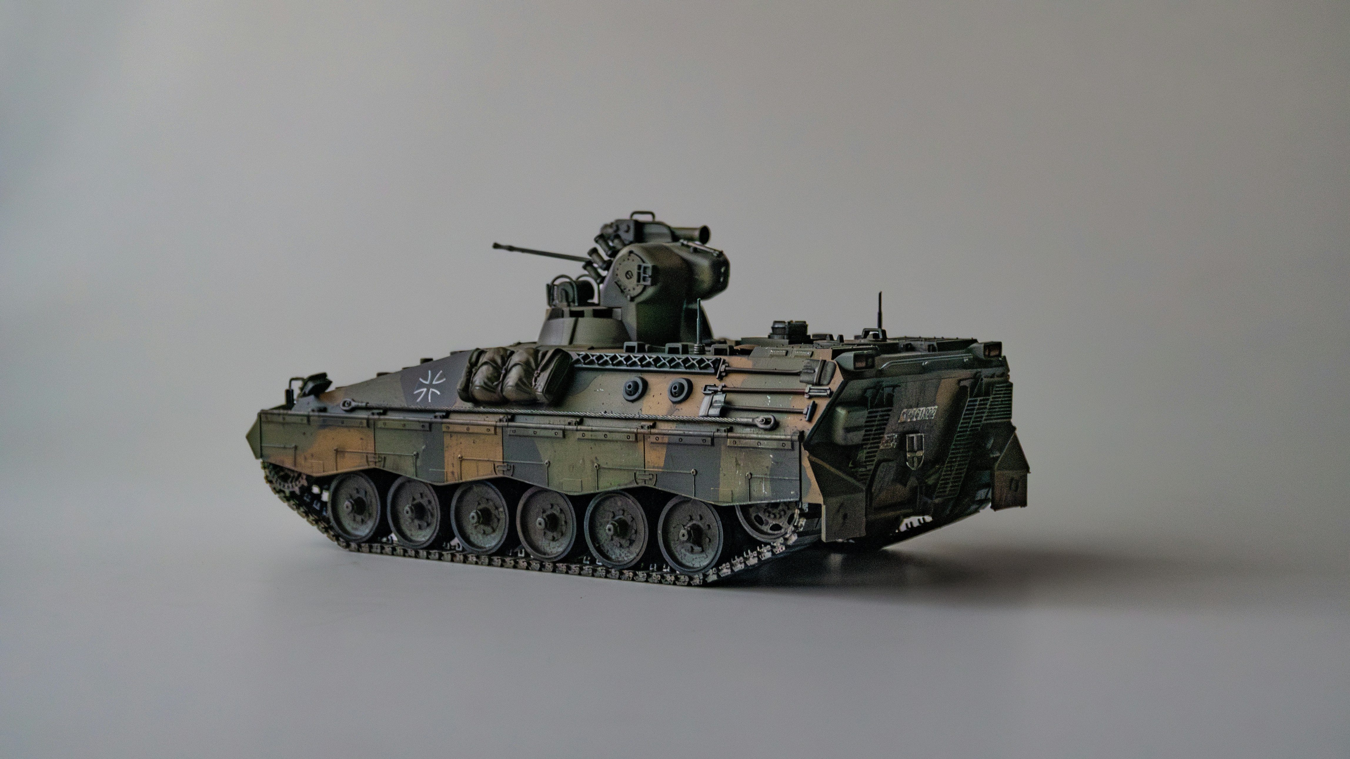 Ein getarnter Militärpanzer ist auf grauem Hintergrund zu sehen