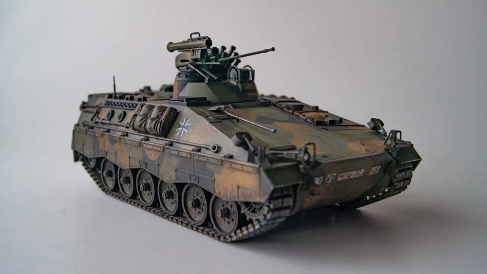 Un tanque de juguete del ejército se muestra sobre una superficie blanca