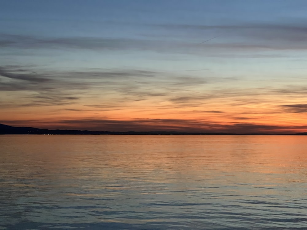 a sunset over a body of water with a boat in the distance