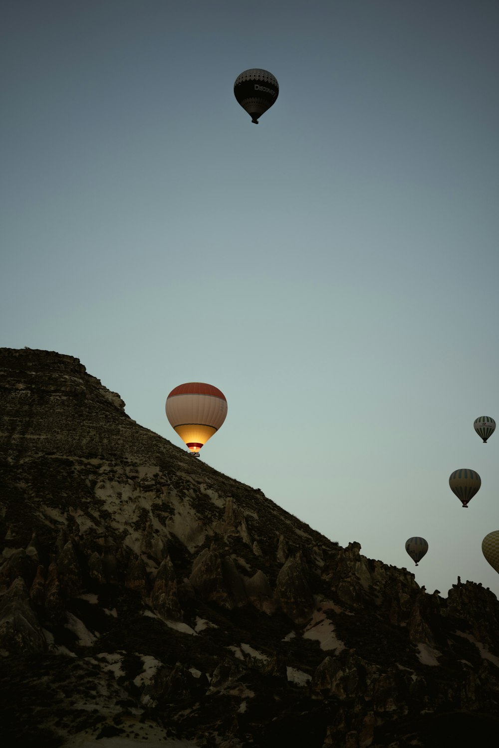 a group of hot air balloons flying over a mountain