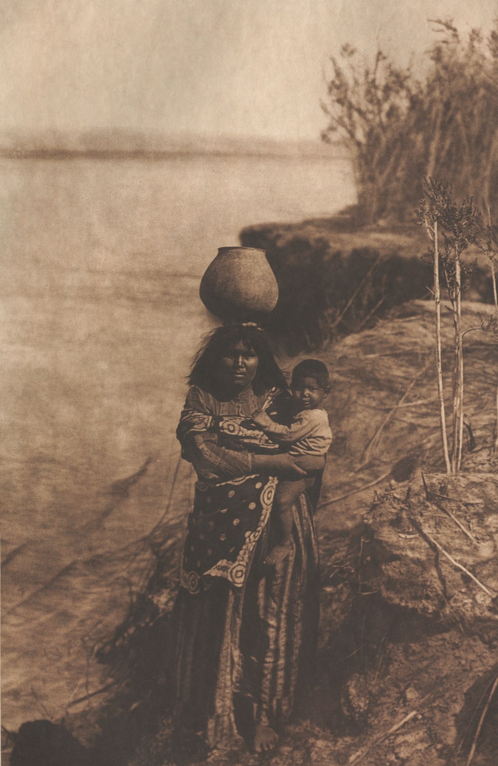 a woman holding a child near a body of water