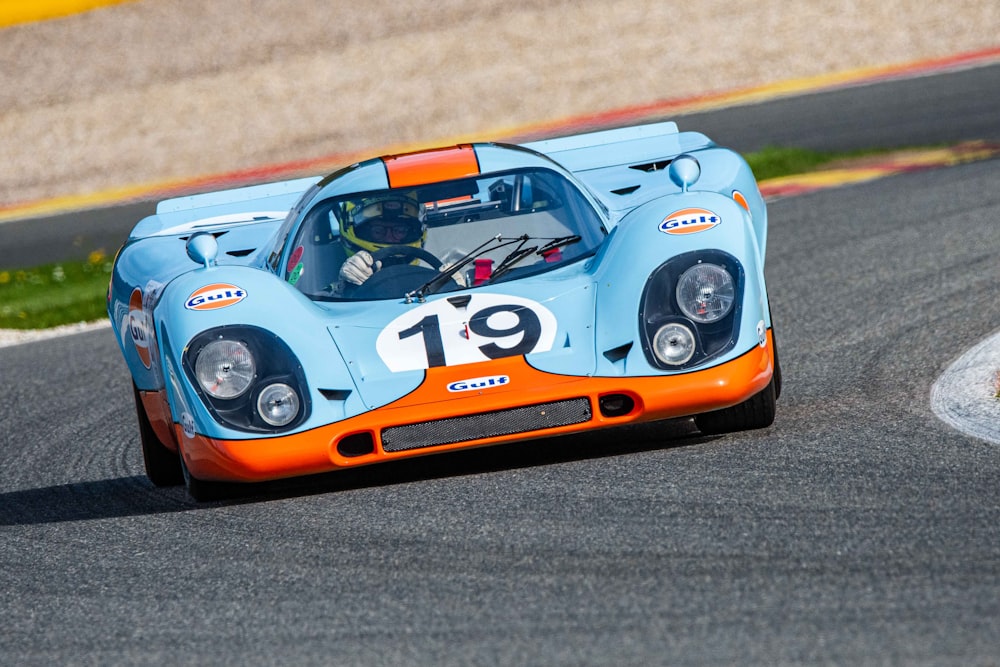 a blue and orange race car driving on a race track