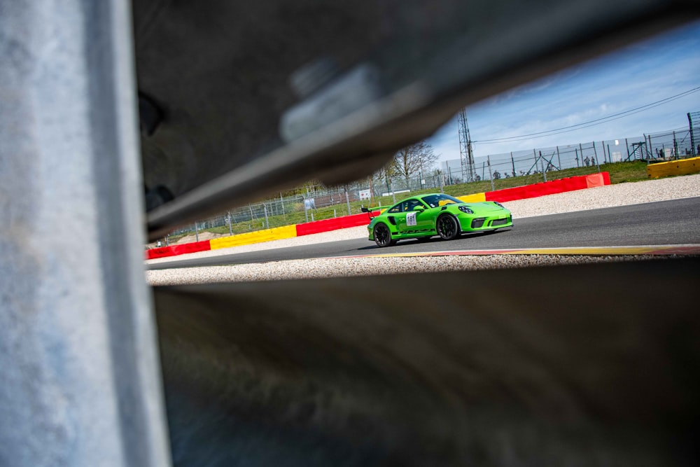 a green sports car driving down a race track