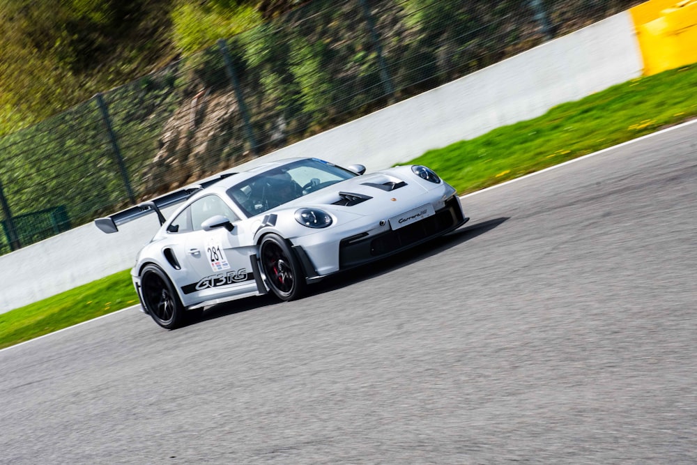 a white sports car driving down a race track