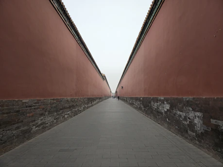 a person walking down a walkway between two red walls