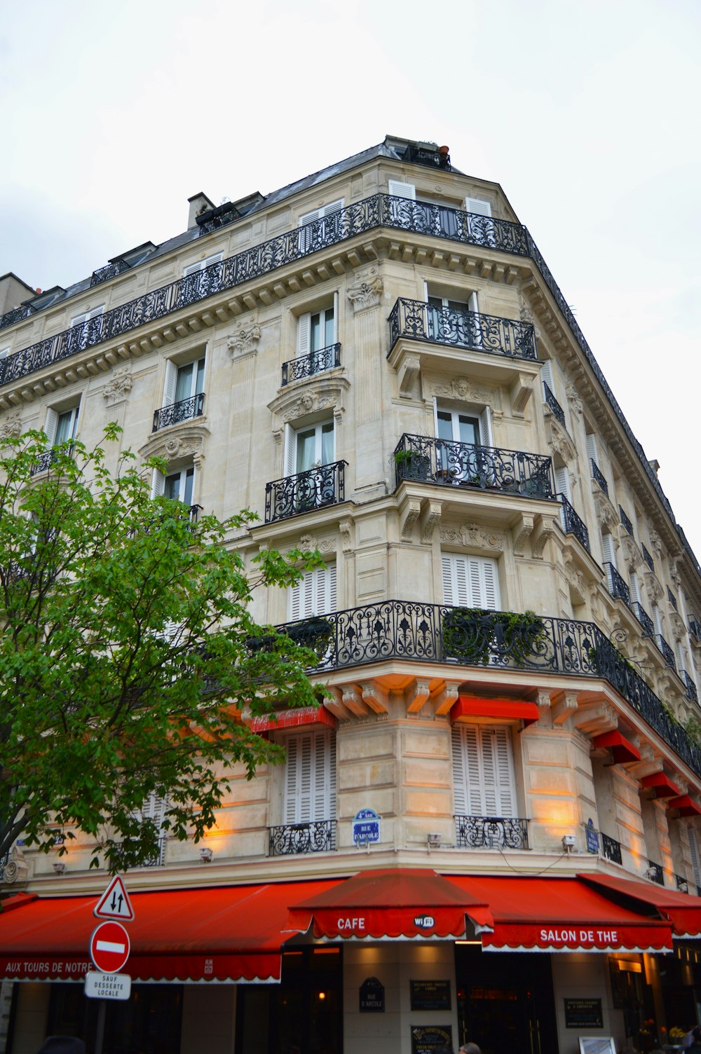 a tall building with balconies and a red awning