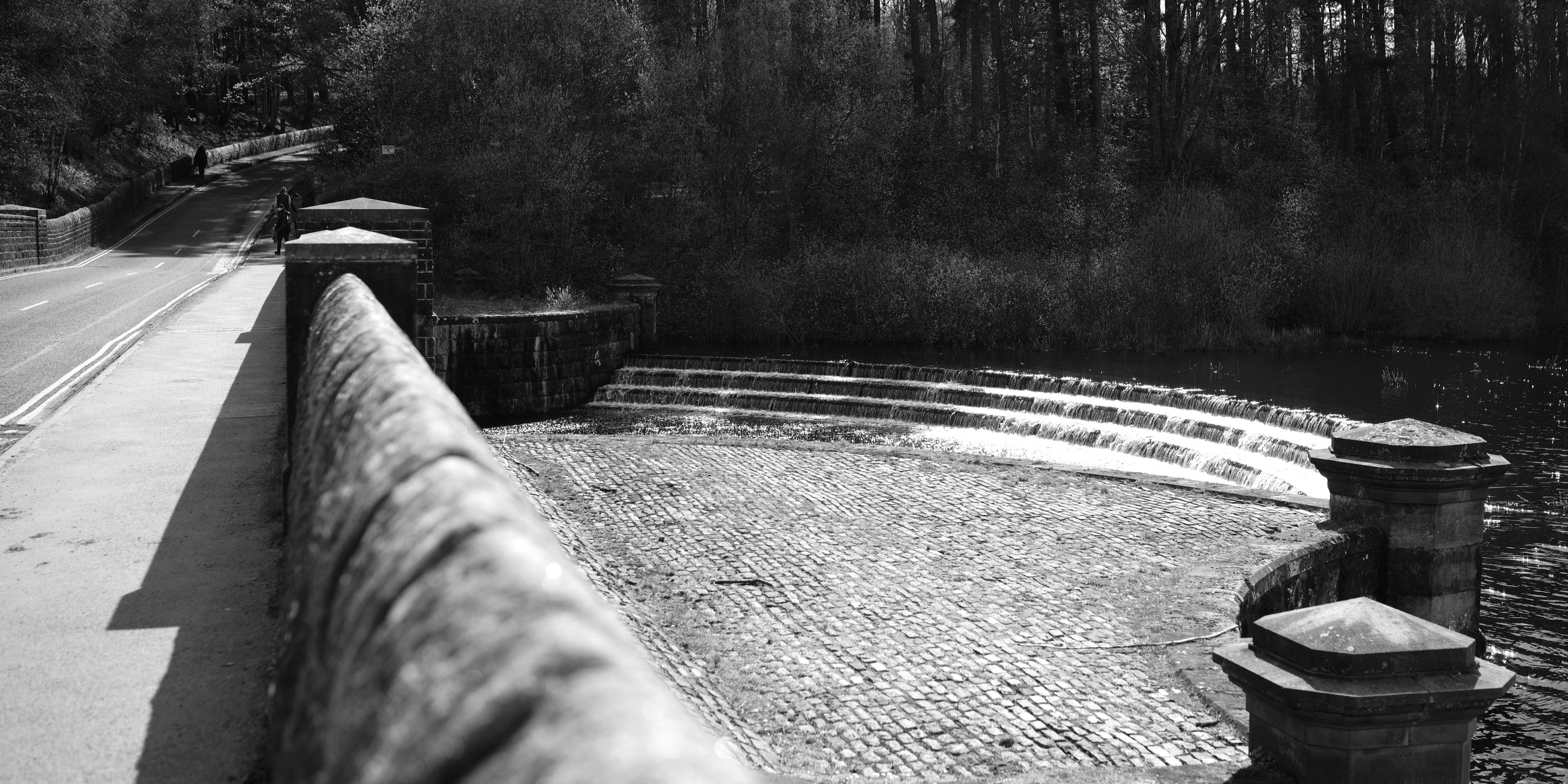a black and white photo of a stone walkway next to a body of water