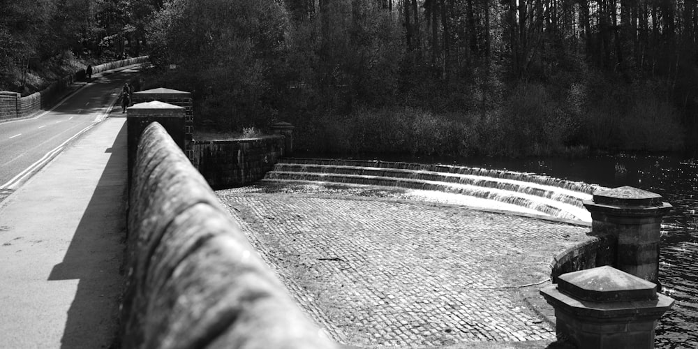 a black and white photo of a stone walkway next to a body of water