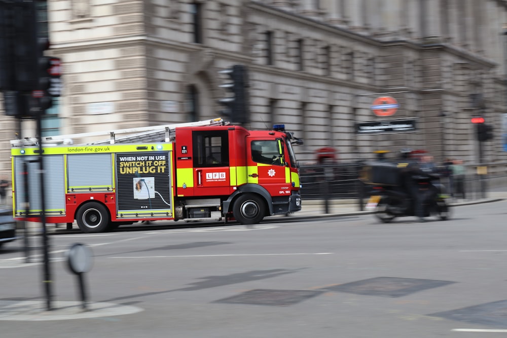 a red and yellow fire truck driving down a street