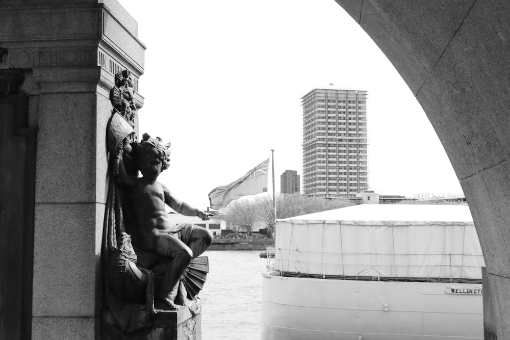 a black and white photo of a statue on a bridge