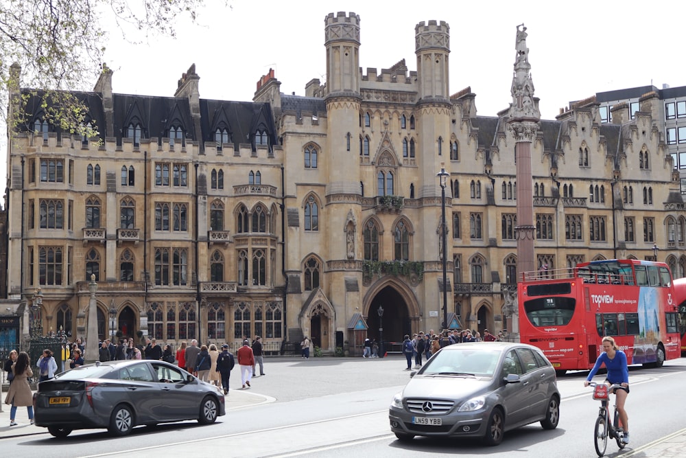 a red double decker bus driving past a tall building