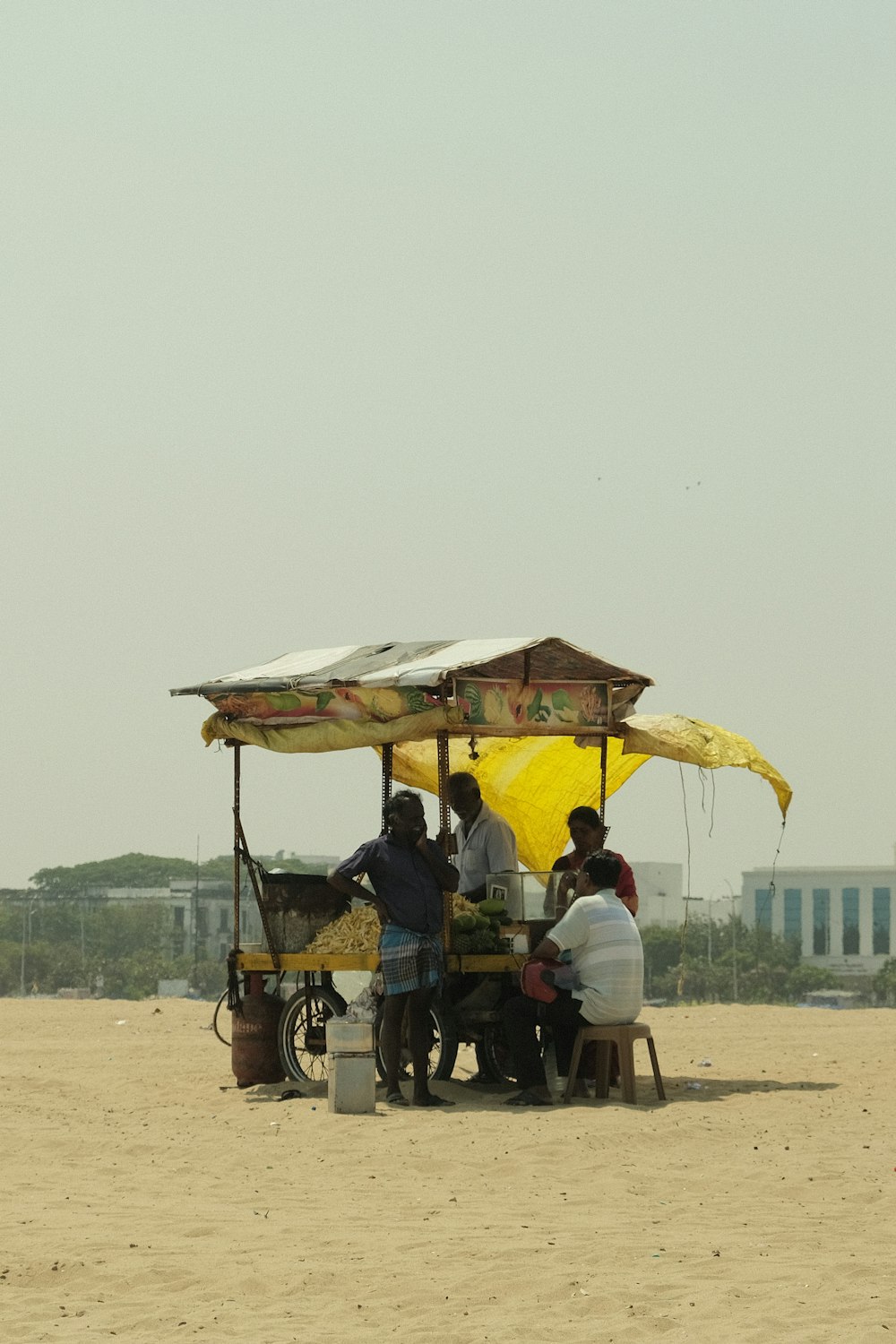 a group of people sitting under a yellow umbrella