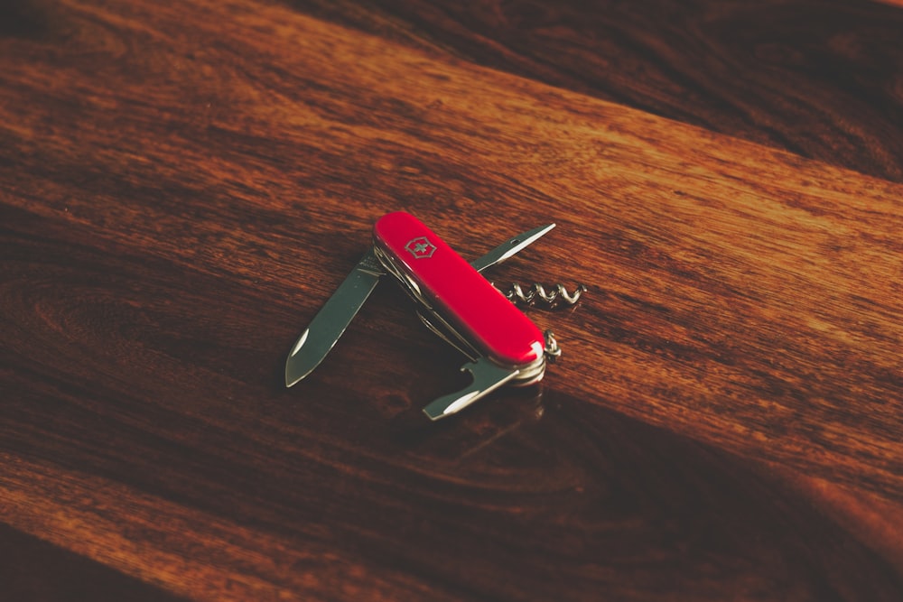 a red swiss army knife sitting on top of a wooden table