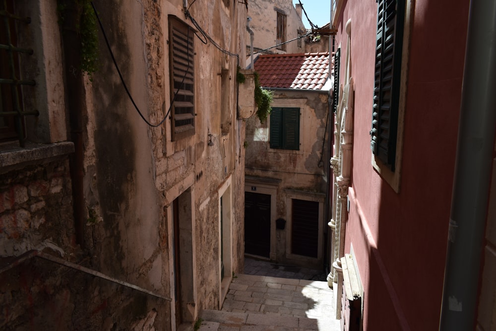 a narrow alleyway between two buildings with shutters