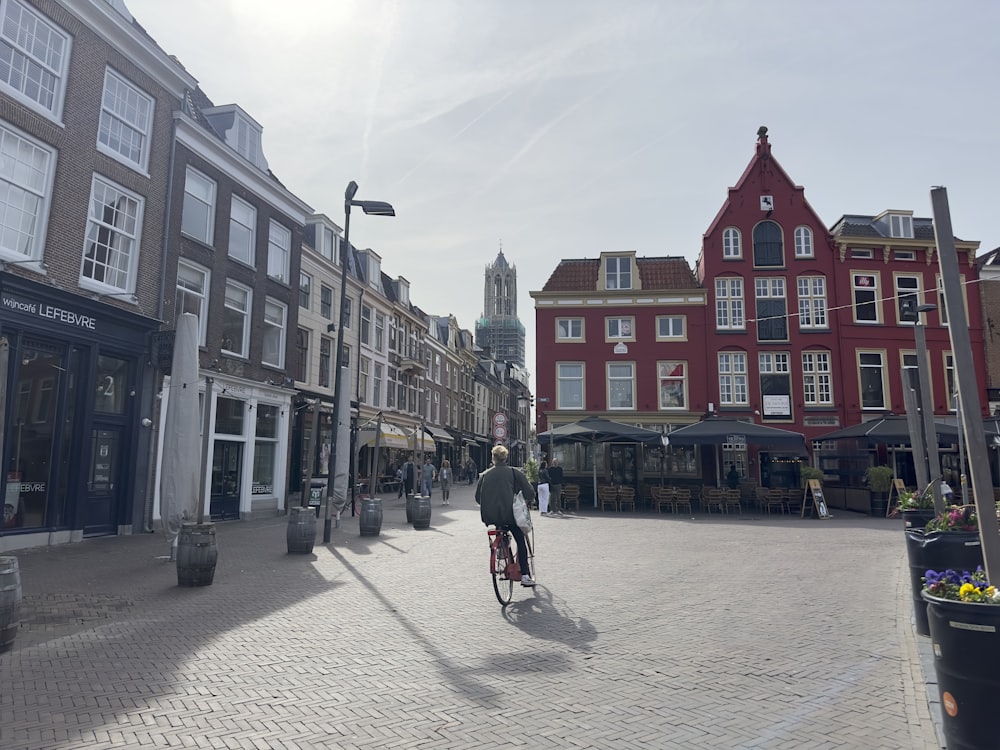 a man riding a bike down a street next to tall buildings