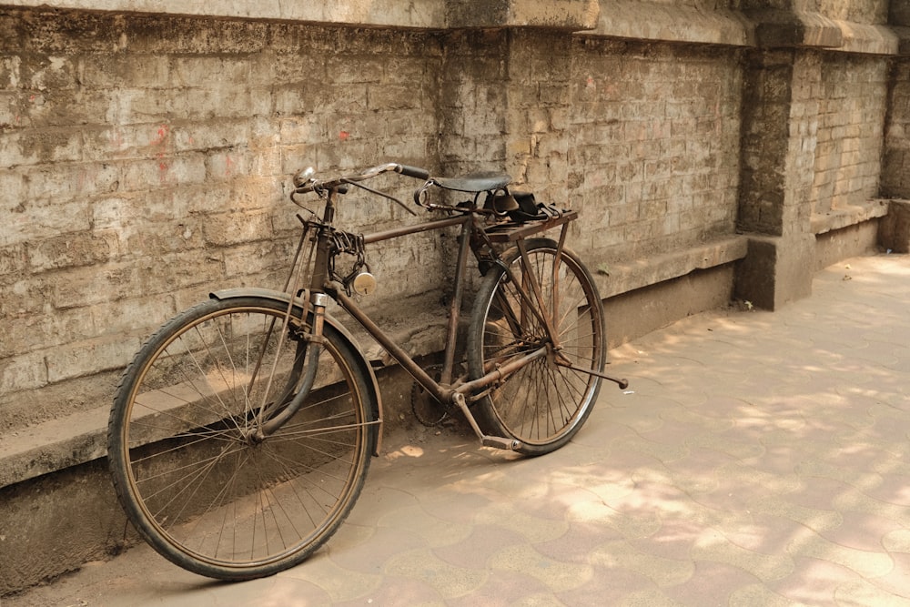 a bicycle parked next to a brick wall