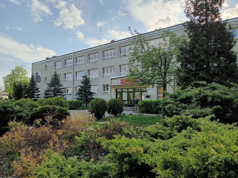 a building with a lot of trees and bushes in front of it