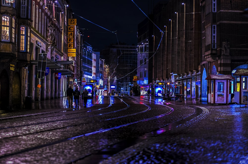 a city street at night with people walking on the sidewalk