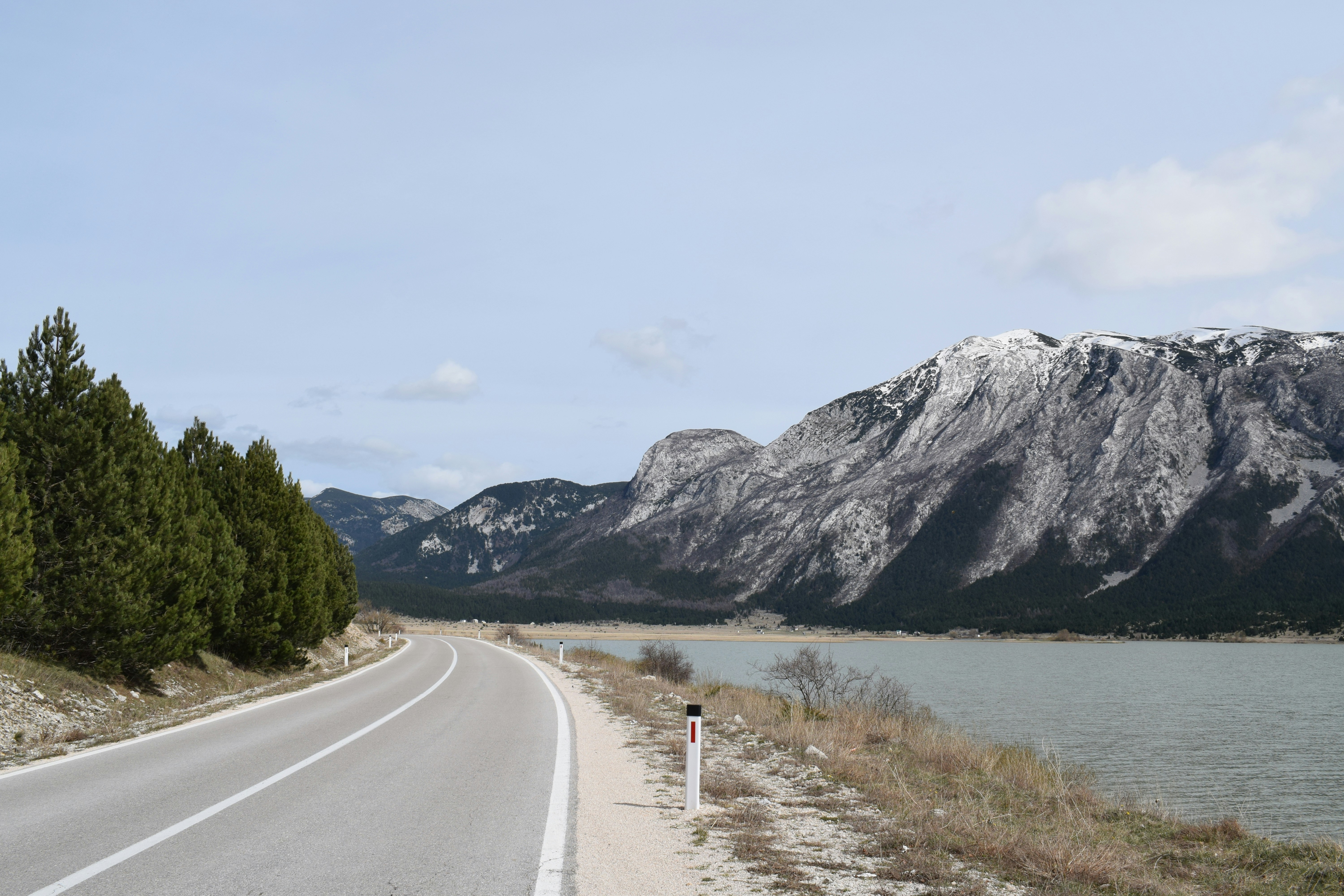a road with a lake and mountains in the background