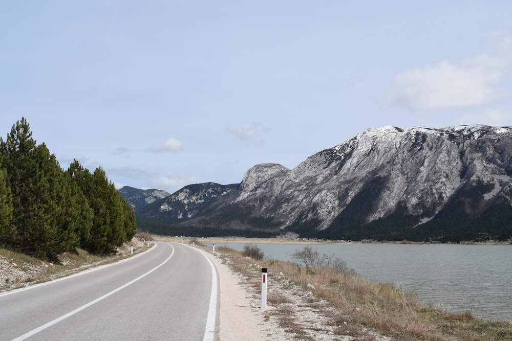 a road with a lake and mountains in the background
