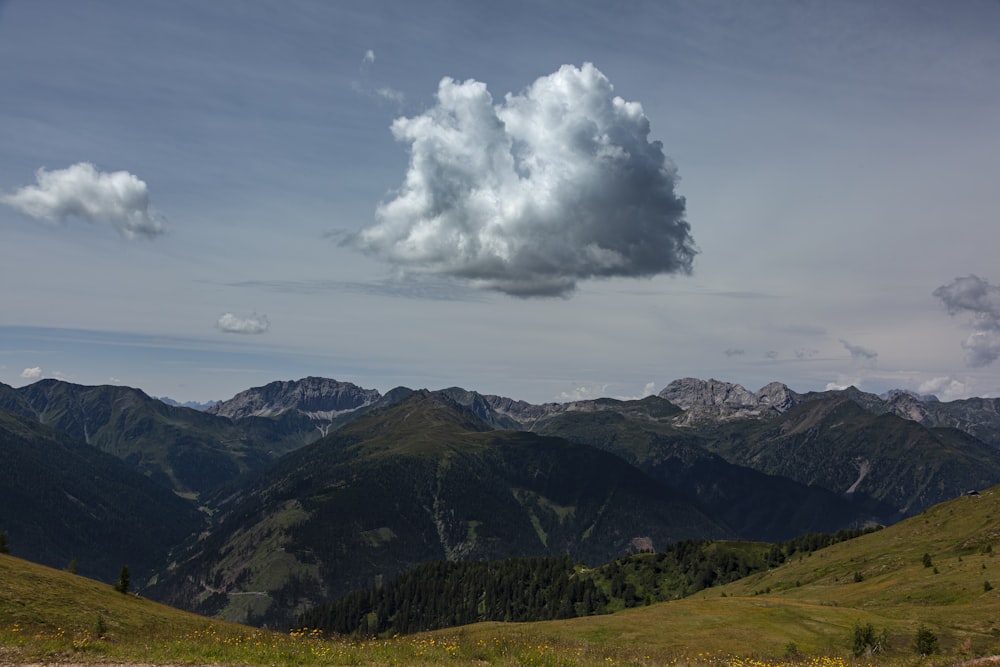 a large cloud is in the sky over a mountain range