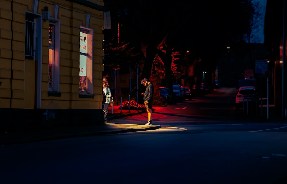 a man and a woman walking down a street at night