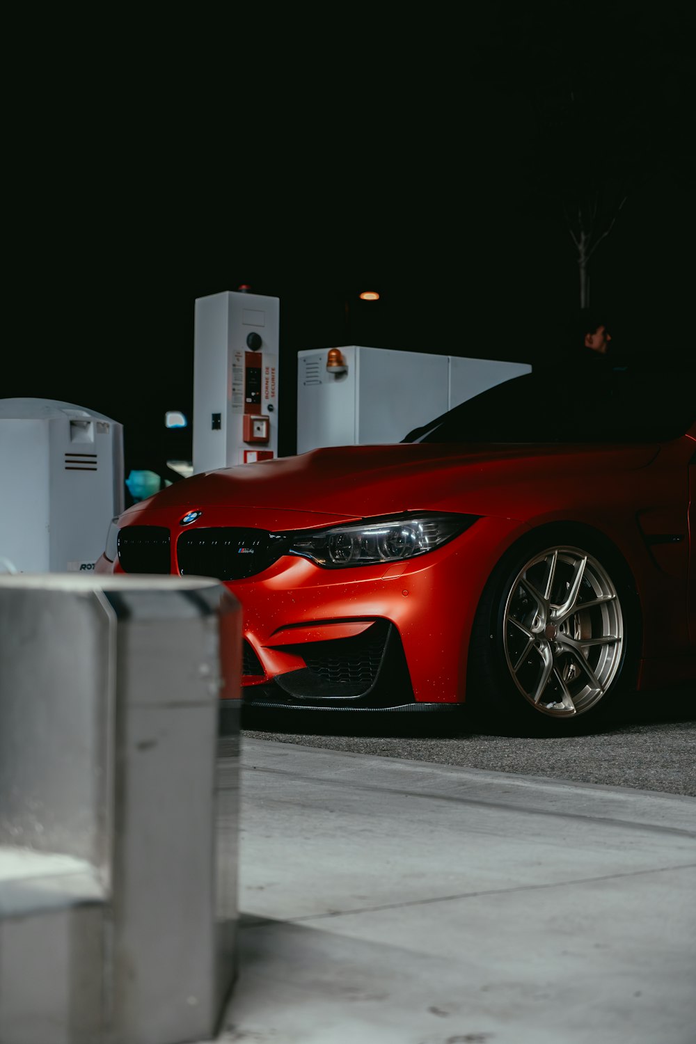 a red car parked in front of a gas station