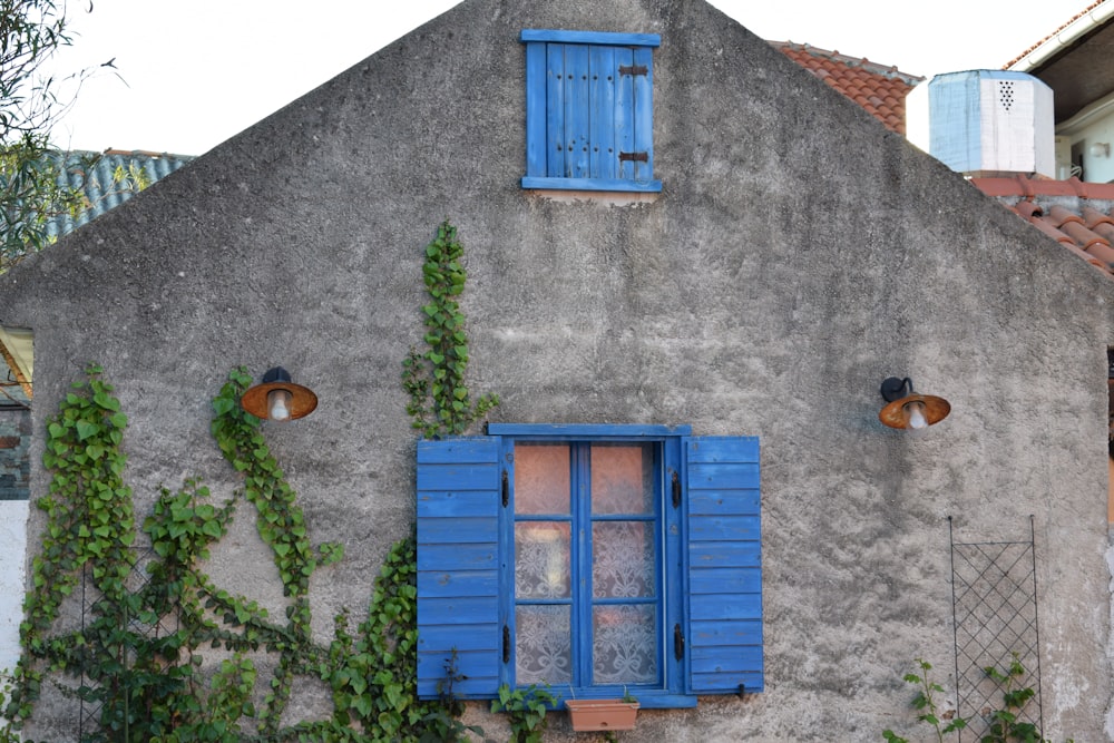 an old building with blue shutters and ivy growing on it