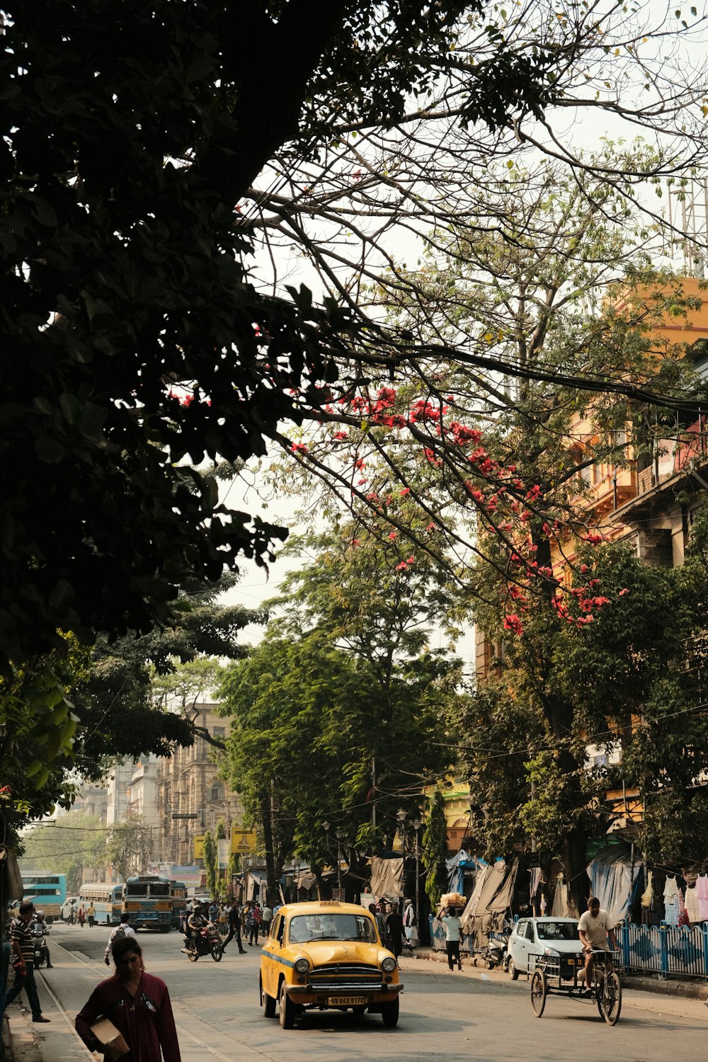 a yellow car driving down a street next to tall buildings