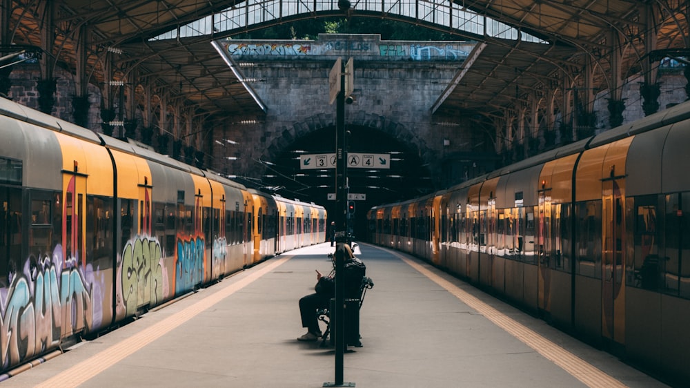a man sitting on a bench next to a train
