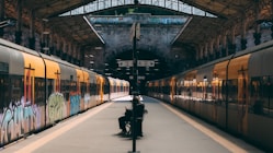 a man sitting on a bench next to a train