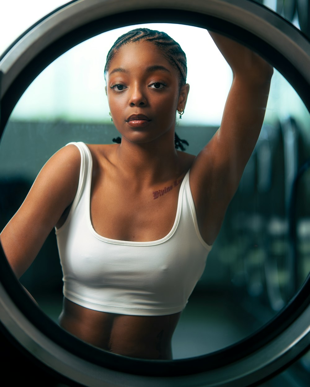 a woman in a white tank top standing in front of a dryer