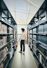 a man walking down a long aisle in a library