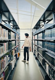 a man walking down a long aisle in a library