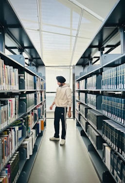 a man walking down a long aisle in a library