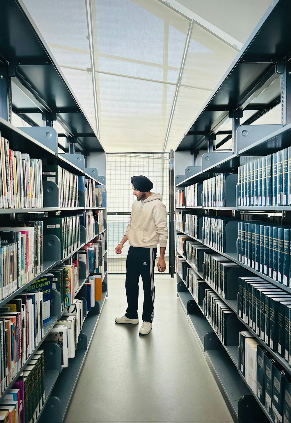 a man walking down a long aisle in a library