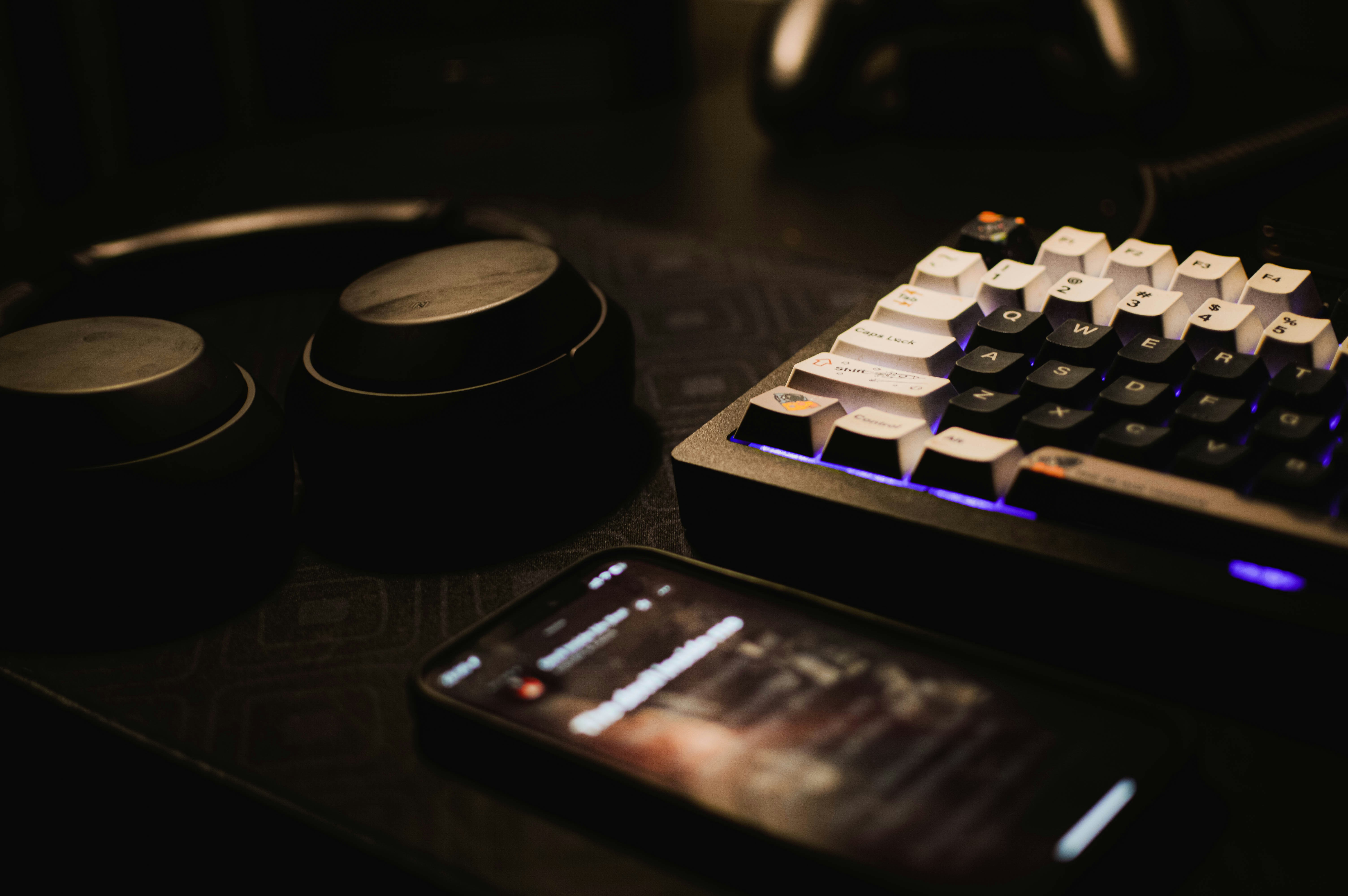 A phone and headphones sit next to a computer as a filmmaker edits his cut. He will use cinematic riser sound effects to build suspense.