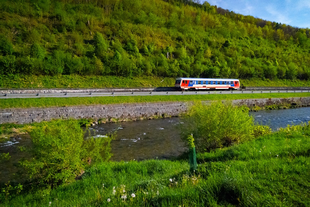a bus driving down a road next to a lush green hillside