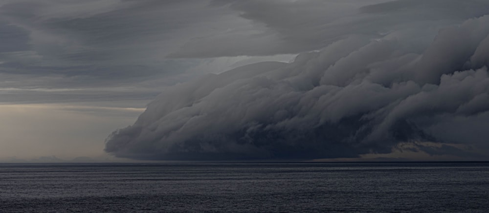 a large storm cloud looms over a body of water