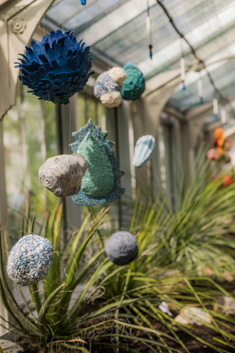 a group of balls hanging from a ceiling in a greenhouse